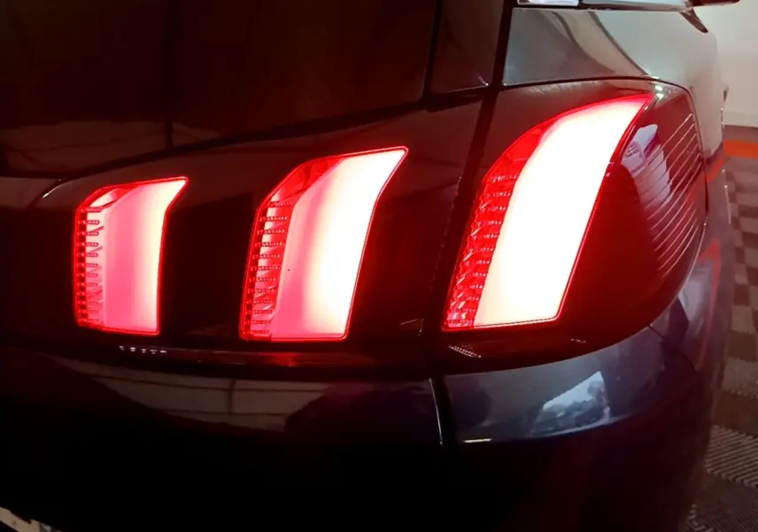 Gros plan sur le feu arrière droit rouge d'un Peugeot 5008 bleu, version 2018, dans un parking intérieur.