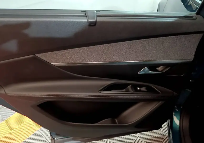 Vue intérieure du panneau de porte côté droit du Peugeot 5008 bleu, avec garniture tissu et commandes électriques.