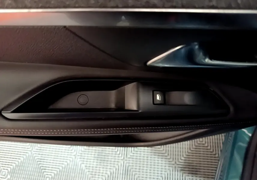 Poignée intérieure côté gauche de la porte d’un Peugeot 5008 bleu, avec bouton de verrouillage visible.