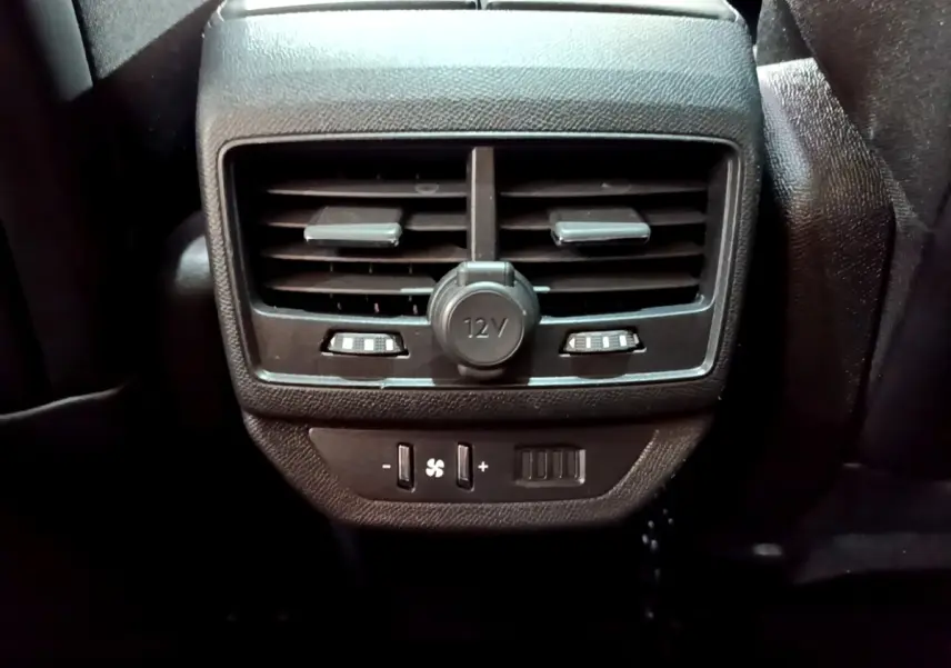 Gros plan sur la ventilation arrière noire avec prise 12V et commandes de climatisation du Peugeot 5008 bleu 2018.