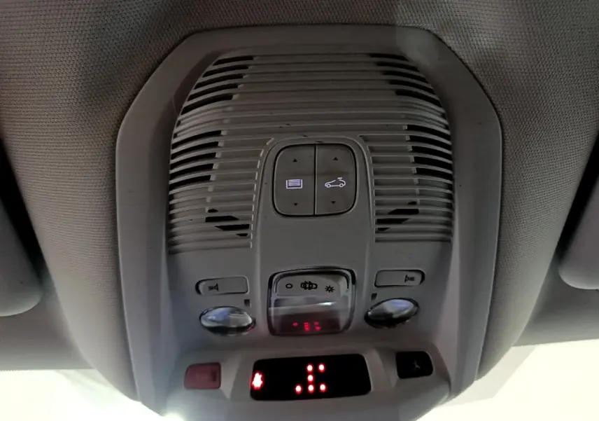 Vue en gros plan du plafonnier intérieur gris du Peugeot 5008 bleu, avec commandes d'éclairage et affichage digital rouge.
