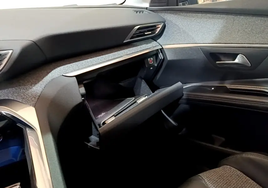 Intérieur côté passager du Peugeot 5008 2018, boîte à gants ouverte, tableau de bord et garnitures noires visibles.