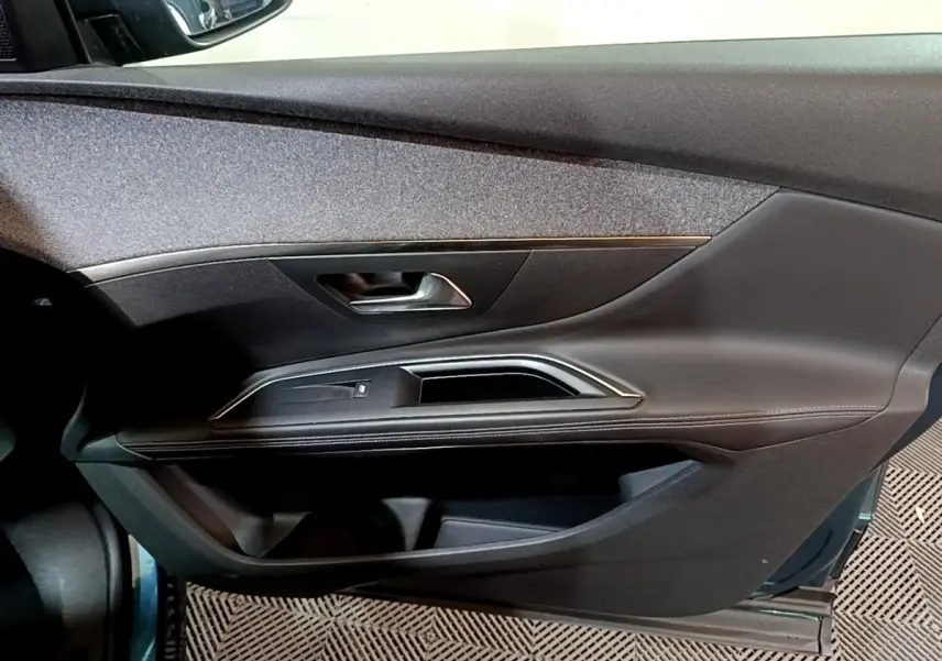 Vue rapprochée de la porte avant gauche du Peugeot 5008 bleu, avec garniture noire et insert décoratif chromé.