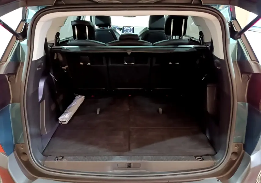 Coffre ouvert vu de l'arrière d'un Peugeot 5008 bleu 2018, montrant l'espace de chargement et sièges rabattus.