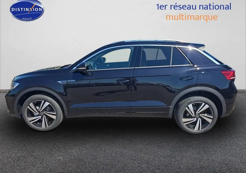 Vue de profil côté gauche d’un Volkswagen T-Roc noir perle avec jantes alliage 18 pouces et barres de toit argentées.