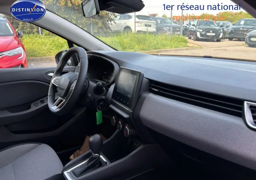 Vue intérieure côté conducteur de la Renault Clio V 2025, tableau de bord et sellerie tissu gris avec écran tactile central.