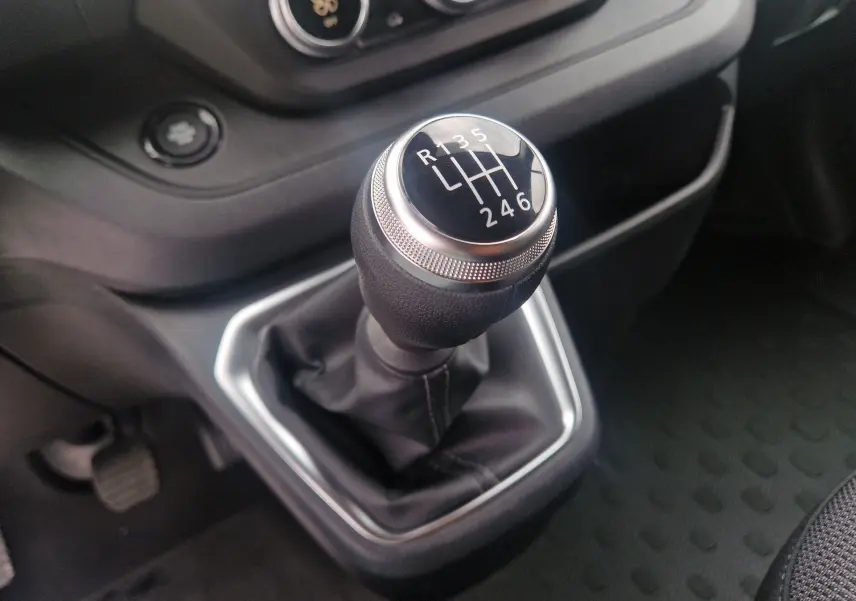 Gros plan sur le levier de vitesses manuel du Renault Trafic Fourgon 2025, entouré d’une console noire.