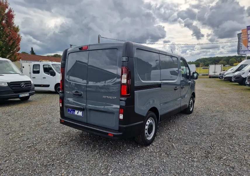 Vue 3/4 arrière droite du Renault Trafic Fourgon gris urbain 2025, avec portes arrière fermées et jantes acier.