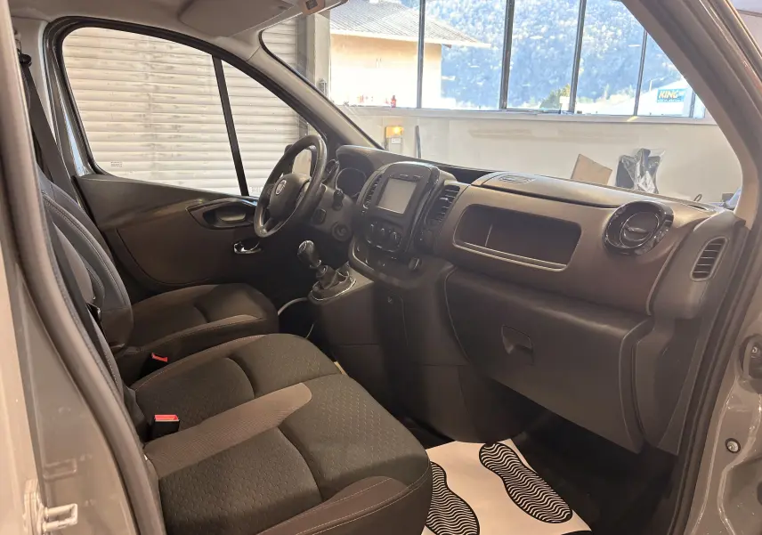 Vue intérieure côté conducteur du Fiat Talento Fourgon gris 2017, montrant le tableau de bord et les sièges en tissu noirs.