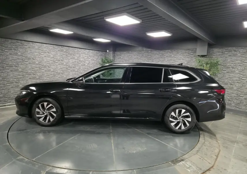 Vue latérale droite d'une Volkswagen Passat SW noire 2024 en hybride essence, avec jantes alliage et vitres teintées.