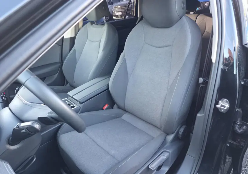 Vue intérieure côté conducteur de la Volkswagen Passat SW noire 2024, sièges tissu gris et volant multifonction cuir.