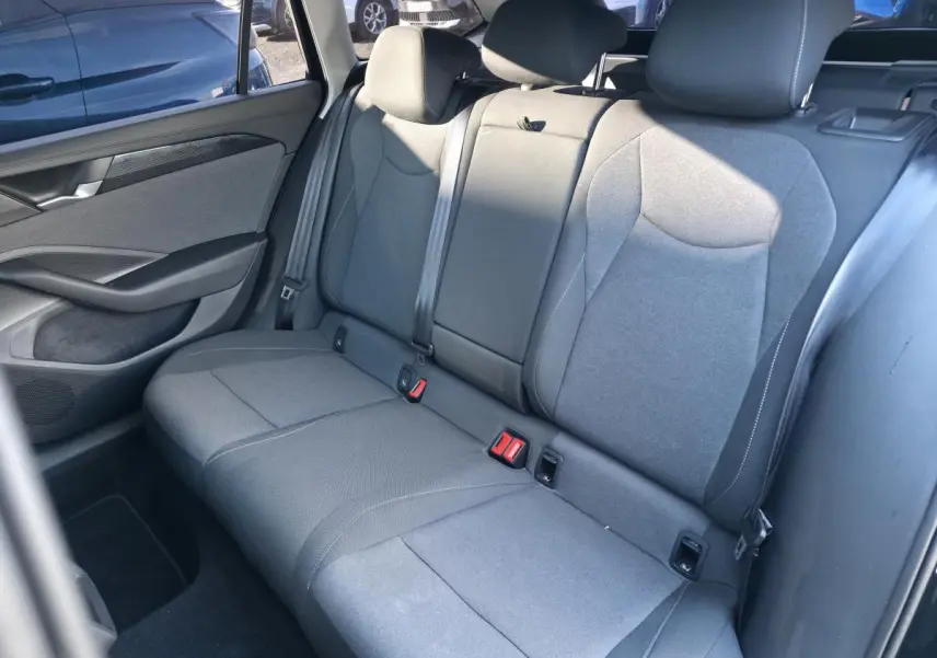 Vue intérieure côté droit des sièges arrière gris tissu de la Volkswagen Passat SW 2024, avec ceintures et appuie-têtes.