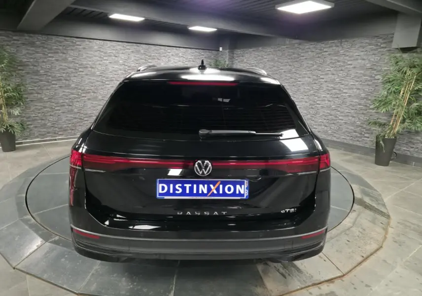Vue arrière d'une Volkswagen Passat SW noire 2024 avec feux arrière LED continus et vitre arrière teintée.