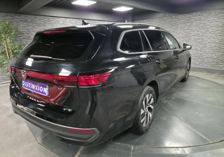 Vue 3/4 arrière droite d'un Volkswagen Passat SW noir métallisé, avec feux arrière LED et jantes alliage.