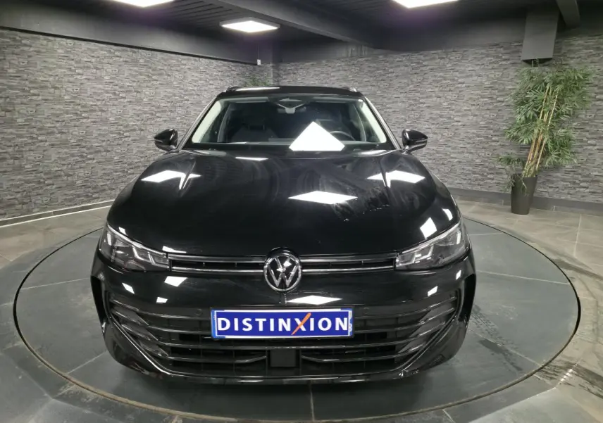 Volkswagen Passat SW noire vue de face dans un showroom avec éclairage et plaque Distinxion.
