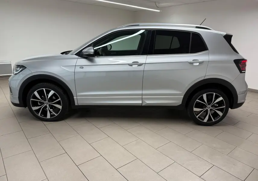 Profil côté gauche du Volkswagen T-Cross 1.5 TSI R-Line 2024 en peinture métallisée Reflet d'Argent avec jantes alliage noires et argent.