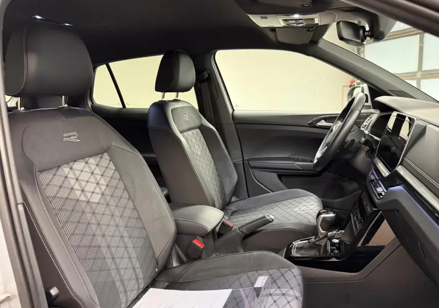 Vue intérieure côté conducteur du Volkswagen T-Cross 1.5 TSI R-Line 2024, sièges noirs avec surpiqûres et logo R brodé.
