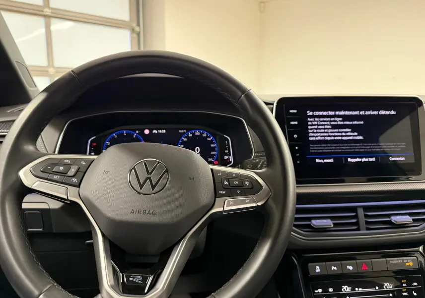 Vue intérieure centrée sur le volant cuir multifonction avec logo VW, tableau de bord digital et écran tactile du Volkswagen T-Cross.