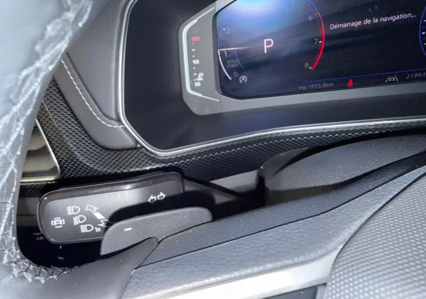 Gros plan sur le combiné d'instruments digital et la commande des feux du Volkswagen T-Cross 1.5 TSI R-Line, intérieur noir.