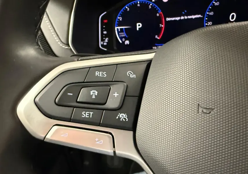 Gros plan sur les commandes du volant cuir du Volkswagen T-Cross 1.5 TSI 150 DSG7 R-Line, tableau de bord digital en arrière-plan.