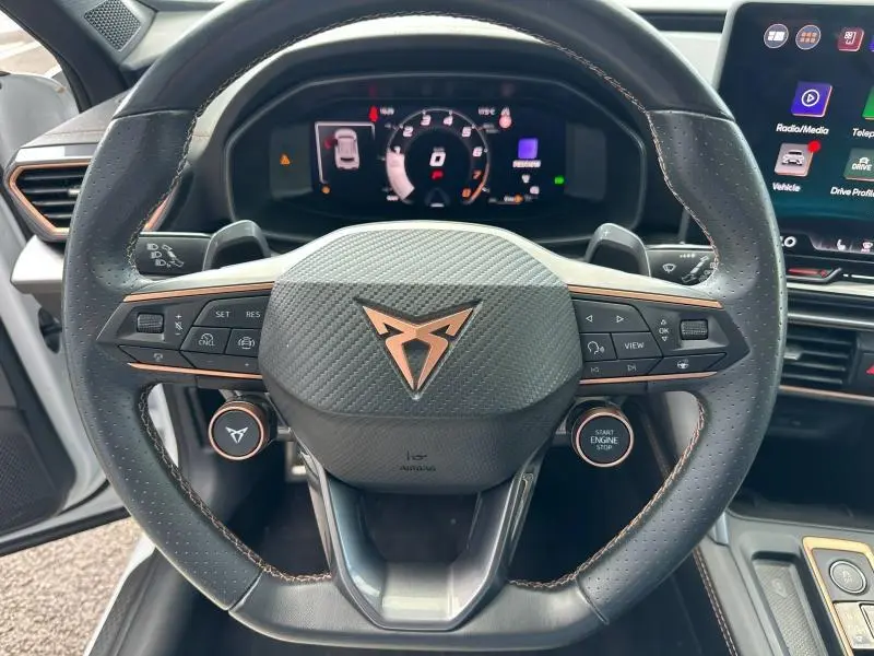Vue rapprochée du volant cuir perforé noir avec logo CUPRA cuivre et commandes multifonctions du Formentor hybride.