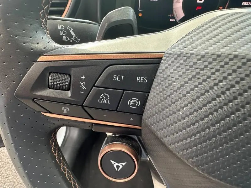 Gros plan sur les commandes multifonctions gauche du volant cuir perforé noir avec surpiqûres cuivrées du CUPRA Formentor blanc Nevada.