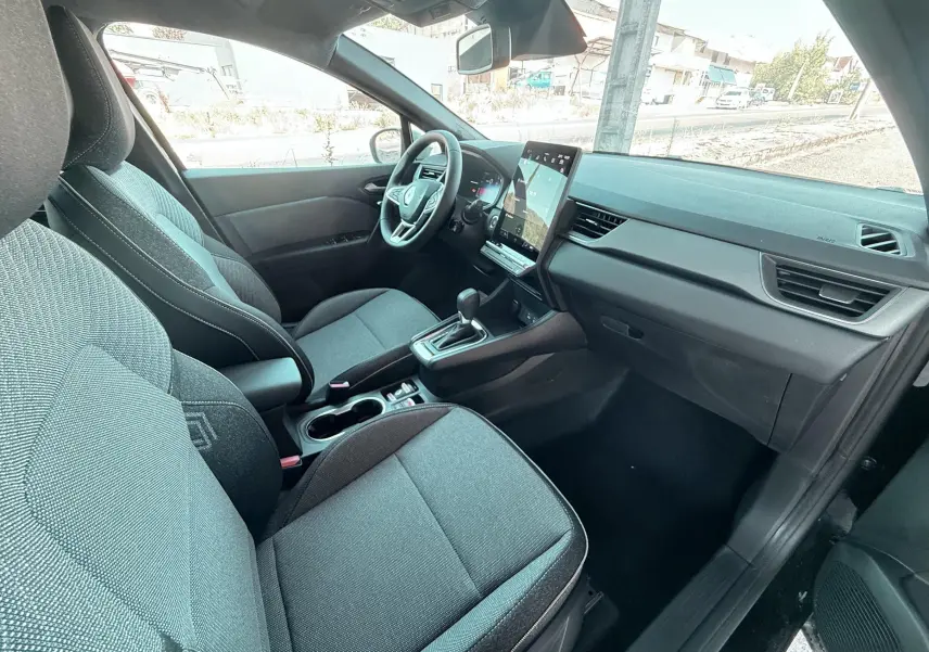 Vue intérieure arrière côté droit du Renault Captur 2025 noir, sièges tissu gris et noir avec appuie-têtes intégrés.