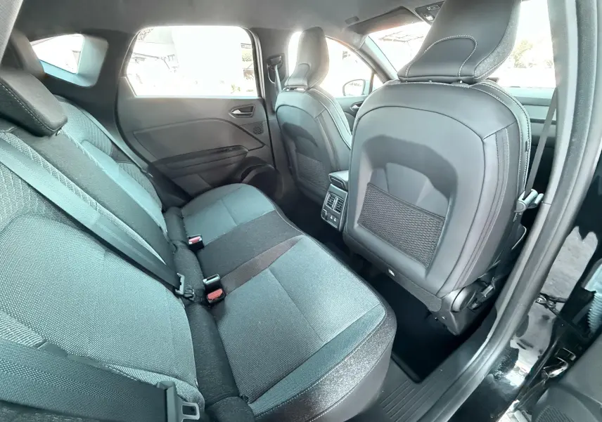 Vue intérieure côté conducteur du Renault Captur noir 2025, montrant sièges tissu gris et écran tactile vertical.
