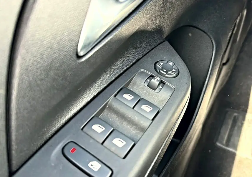 Gros plan sur les commandes de lève-vitres électriques côté gauche d'une Opel Corsa noire 2025.