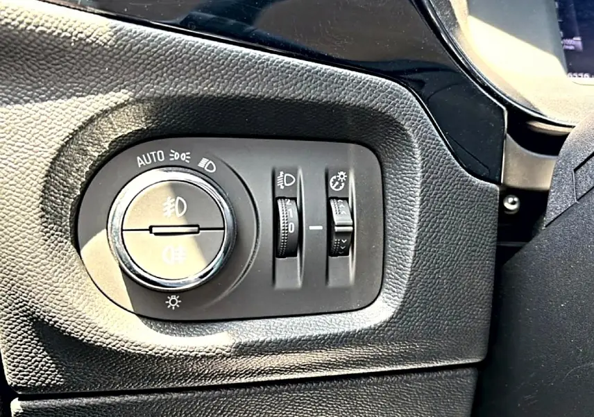 Détail du panneau de commande des phares noir à gauche du volant dans l’Opel Corsa 1.2 turbo 100 édition 2025.