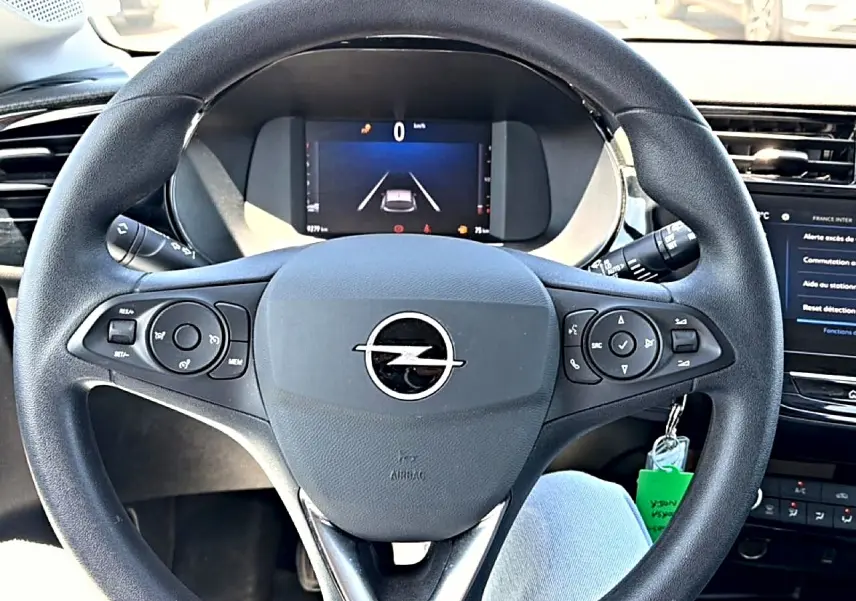 Vue intérieure centrée sur le volant noir multifonction de l’Opel Corsa 1.2 turbo 100 edition avec tableau de bord numérique.