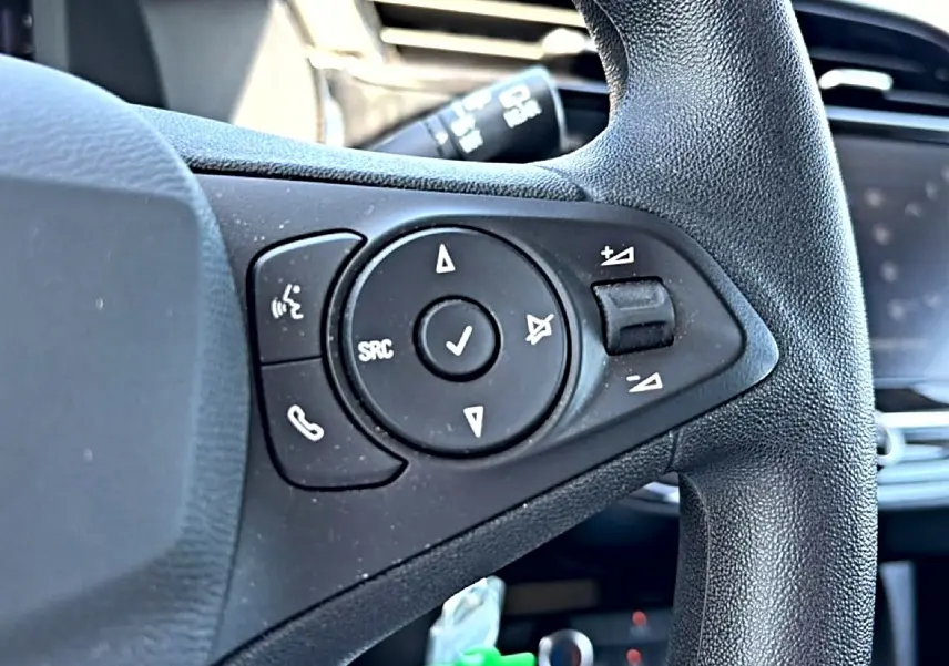 Gros plan sur les commandes audio au volant noir de l’Opel Corsa 1.2 turbo 100 edition 2025, intérieur visible flou.