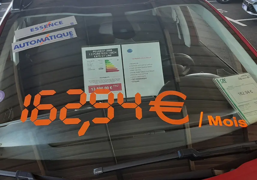 Vue avant d'une Peugeot 2008 rouge Ultimate Metal avec affichage du prix mensuel sur le pare-brise.
