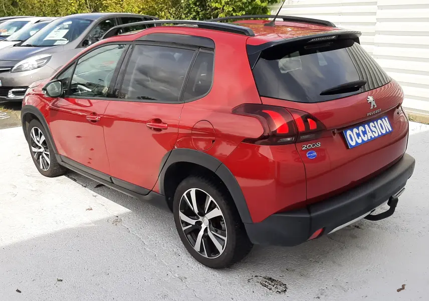 Peugeot 2008 rouge Ultimate Metal vue 3/4 arrière droit, avec barres de toit et jantes alliage noires.