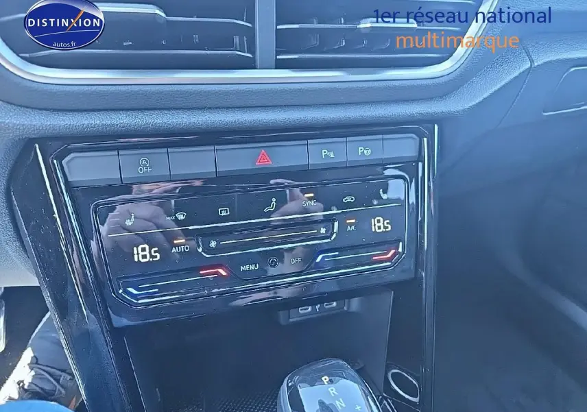 Vue rapprochée de la console centrale noire brillante du Volkswagen T-Roc 2025 avec commandes climatisation digitale et levier de boîte auto.
