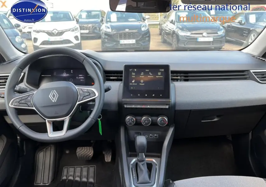 Vue intérieure avant de la Renault Clio V gris foncé, montrant le volant multifonction et l’écran tactile central.