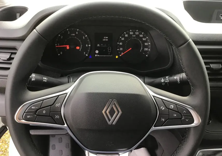 Vue rapprochée du volant noir de Renault Trafic Fourgon 2025 avec commandes intégrées et tableau de bord visible.