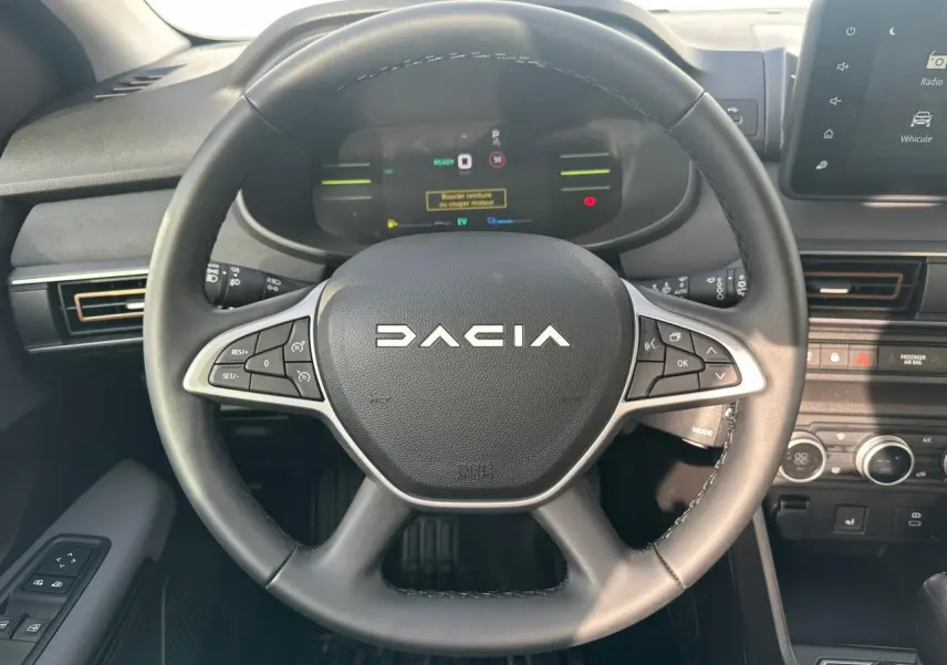 Vue rapprochée du volant noir de la Dacia Jogger 2025 avec commandes intégrées et tableau de bord numérique.