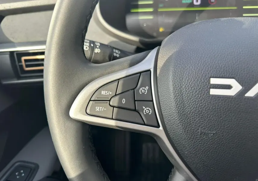 Gros plan sur le volant noir du Dacia Jogger 2025, montrant les commandes de régulateur de vitesse côté gauche.