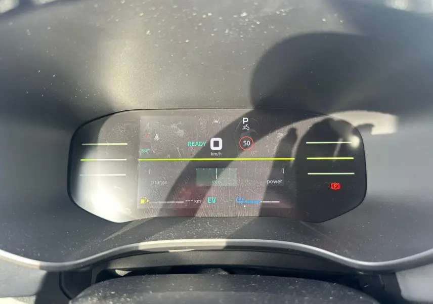 Vue rapprochée du tableau de bord numérique du Dacia Jogger hybride, affichant la vitesse à 0 km/h et indicateurs eco et EV.