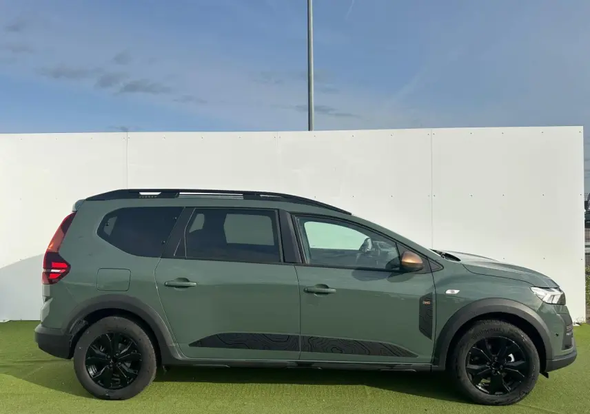 Vue latérale droite d'un Dacia Jogger 2025 kaki lichen avec jantes noires et barres de toit modulaires.