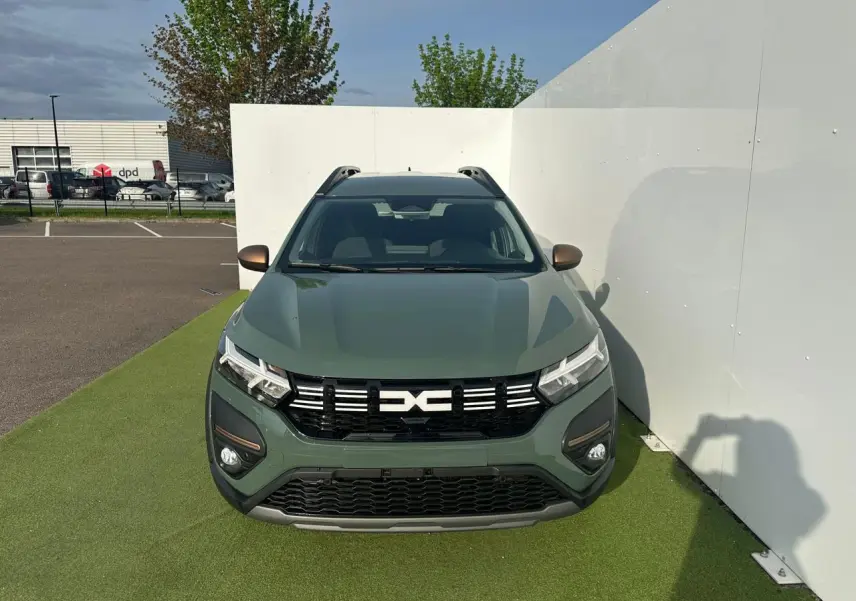 Vue avant du Dacia Jogger 2025 en kaki lichen métal avec calandre noire et barres de toit visibles.