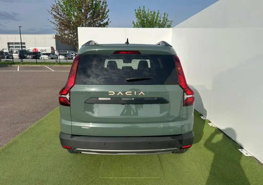 Vue arrière d'un Dacia Jogger hybride 2025 en kaki lichen avec logo blanc et feux LED verticaux distinctifs.