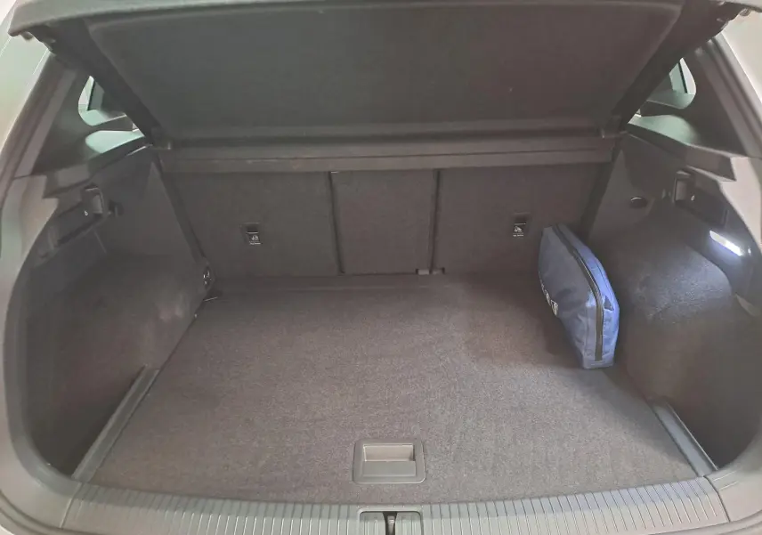 Coffre ouvert du Volkswagen Tiguan blanc pur 2023, vue arrière montrant un espace de chargement avec trousse bleue.
