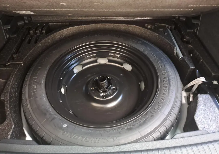 Vue rapprochée de la roue de secours compacte noire dans le coffre du Volkswagen Tiguan blanc pur 2023.