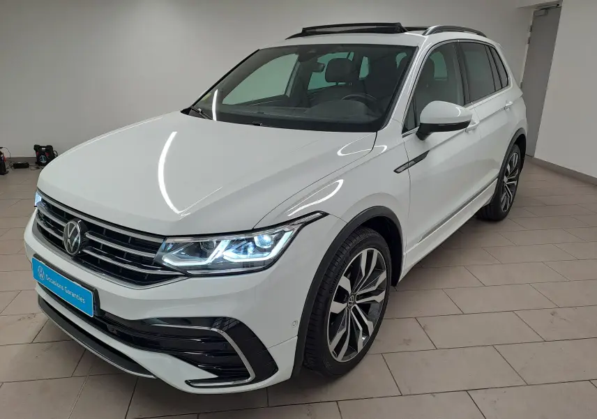 Vue 3/4 avant d'un Volkswagen Tiguan blanc pur avec jantes alliage 20'' Suzuka et toit ouvrant panoramique visible.