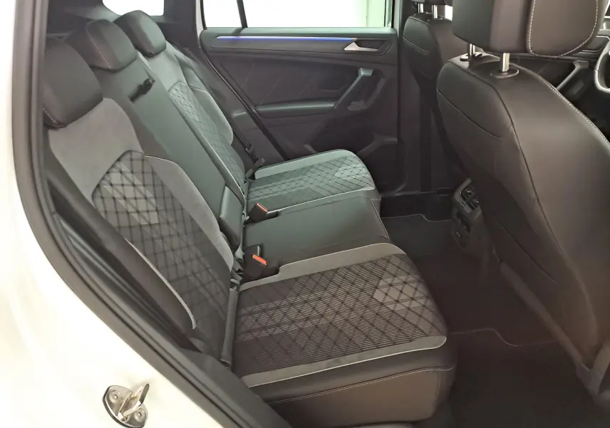 Vue intérieure côté gauche des sièges arrière du Volkswagen Tiguan 2.0 TDI blanc avec sellerie tissu et cuir noir à motifs géométriques.
