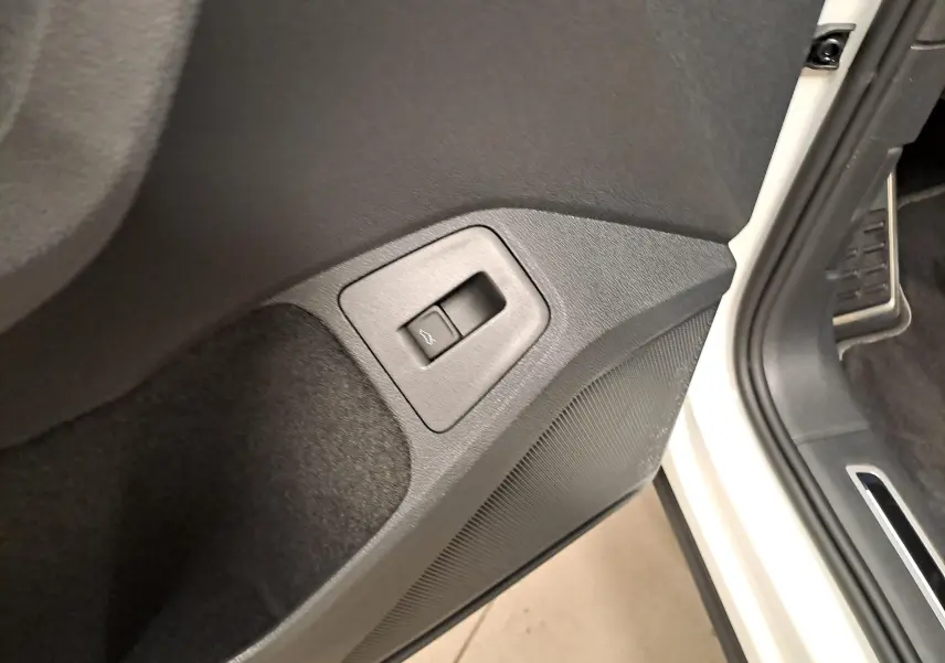 Détail du bouton d'ouverture du coffre sur la porte côté conducteur d'un Volkswagen Tiguan blanc pur 2023.