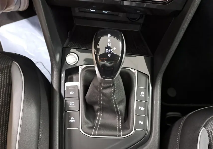 Vue rapprochée de la console centrale du Volkswagen Tiguan 2023, avec levier de vitesse DSG7 et boutons de contrôle autour.