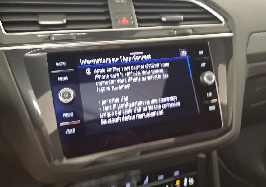 Écran tactile central du Volkswagen Tiguan 2023 affichant les options Apple CarPlay, entouré de commandes et finition intérieure noire.